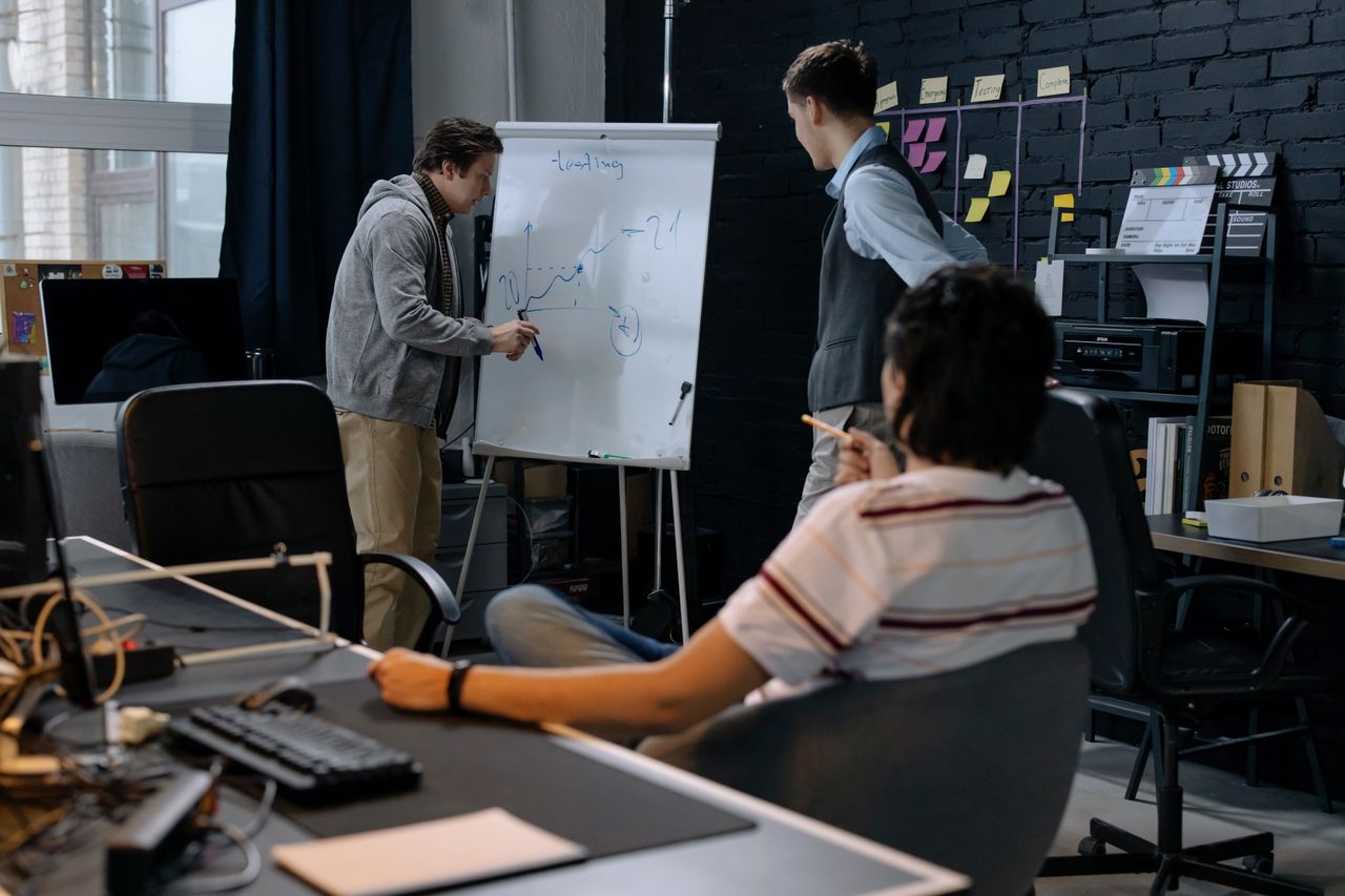 service-05 Business team in a modern office brainstorming ideas on a whiteboard. Engaged discussion and planning.