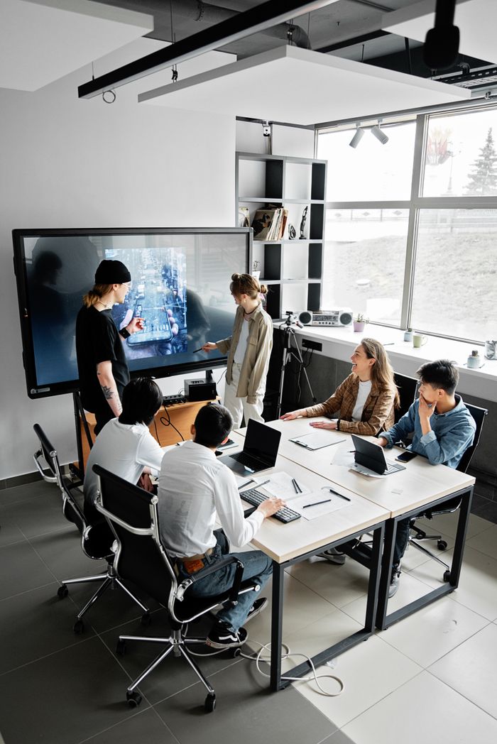 Modern office meeting with diverse team using technology for collaboration.