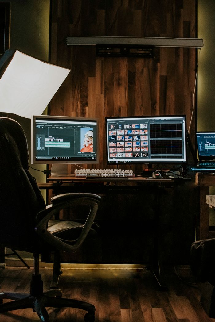 A modern home office setup with dual computer monitors, keyboard, and stylish lighting.